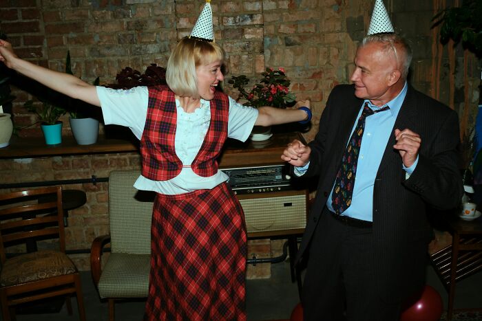 A man and woman wearing party hats dancing and celebrating at a work Christmas party with wild stories.