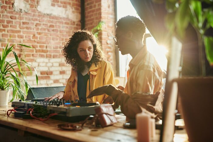 Two people discussing music equipment in a cozy room, capturing moments from wild work Christmas parties.