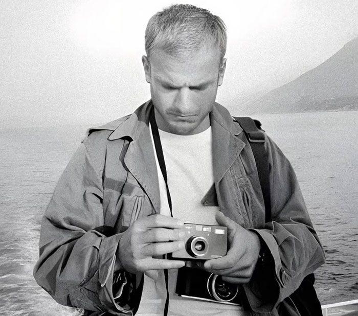 Black and white photo of a VF photographer holding a camera near the sea, relating to Karoline Leavitt close-up defense. Black and white photo of a VF photographer holding a camera near the sea, relating to Karoline Leavitt close-up defense.