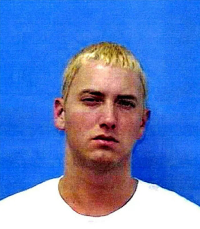 Infamous celebrity mugshot of a young man with blond hair against a blue background, related to celebrity arrests.