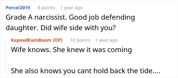 Red dog wearing a Christmas sweater sitting by a decorated mil house with festive holiday lights at night.