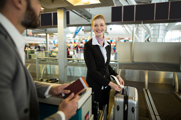 Airline worker smiling at passenger while handling luggage at airport counter amid luggage policy dispute. Airline worker smiling at passenger while handling luggage at airport counter amid luggage policy dispute.