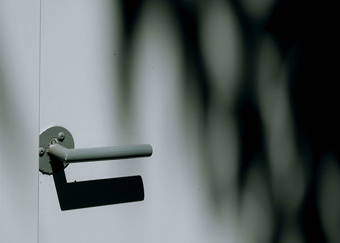 Close-up of a closet door handle casting a shadow, illustrating the topic of a guy venting online about closing the closet door. Close-up of a closet door handle casting a shadow, illustrating the topic of a guy venting online about closing the closet door.