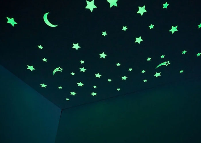 Glowing green stars and crescent moons on a dark ceiling illustrating a peaceful night sky scene. Glowing green stars and crescent moons on a dark ceiling illustrating a peaceful night sky scene.