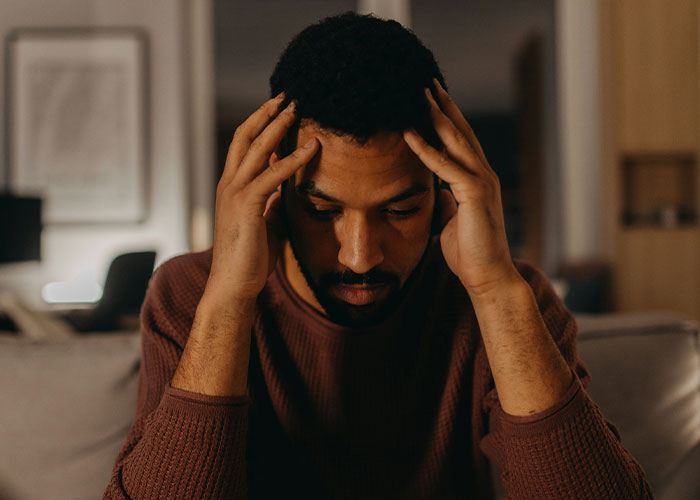 Man feeling stressed and upset indoors after his girlfriend publicly claps back and ends their relationship. Man feeling stressed and upset indoors after his girlfriend publicly claps back and ends their relationship.