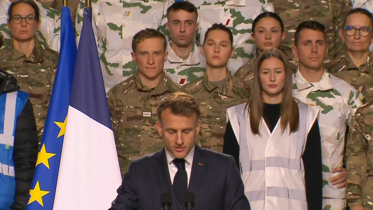 French soldier standing behind Macron during a speech, displaying unusual behavior before abruptly leaving the stage.