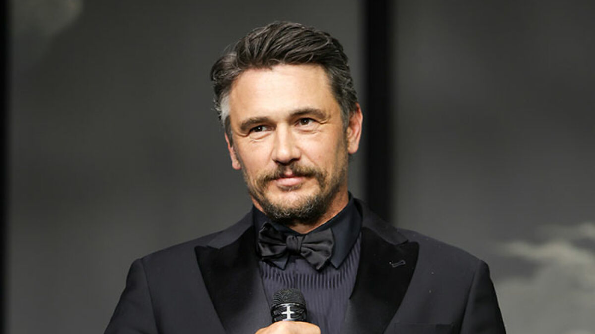 James Franco in a black tuxedo speaking into a microphone at an event after being cast out of Hollywood.