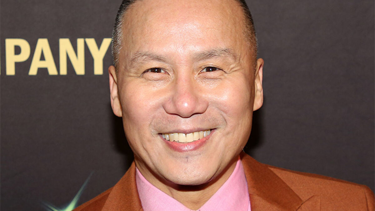 BD Wong, Jurassic World star, smiling at an event while wearing a brown suit jacket and pink shirt.