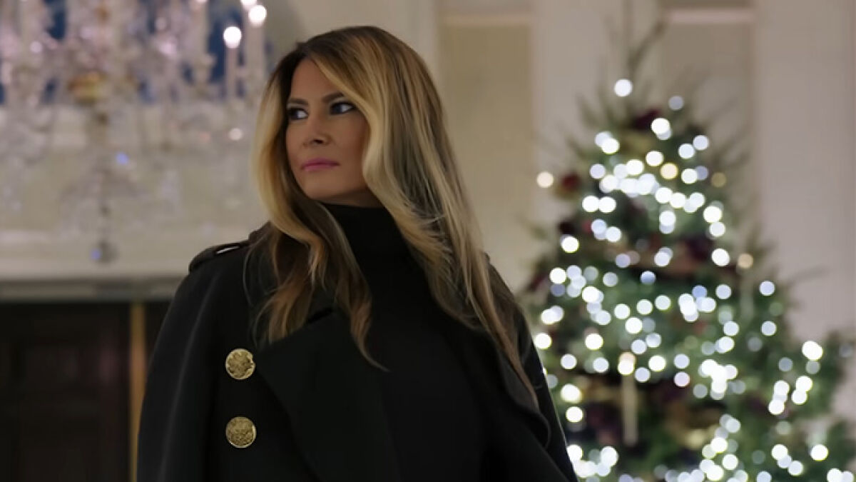 Melania Trump standing indoors near a decorated Christmas tree, highlighting her new Christmas ornament controversy.
