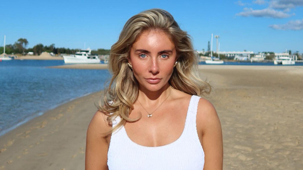 Adult star Bonnie Blue posing on a sunny beach with boats in the background during a controversial tour.