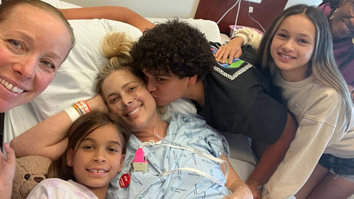 Netflix star and mom of three lying in hospital bed surrounded by family showing love and support in a heartfelt moment
