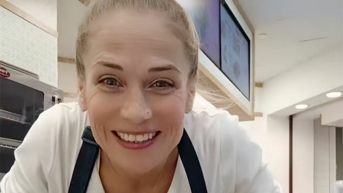 Female Cinnabon worker smiling inside store, linked to viral tirade and revealing a criminal past in recent news.