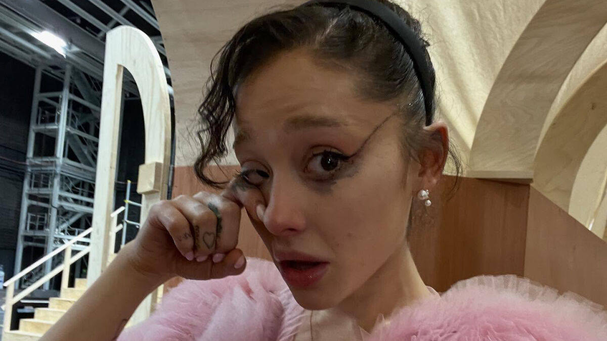 Woman with smudged makeup wiping tears, highlighting Ariana Grande struggles and not in a healthy place discussion.