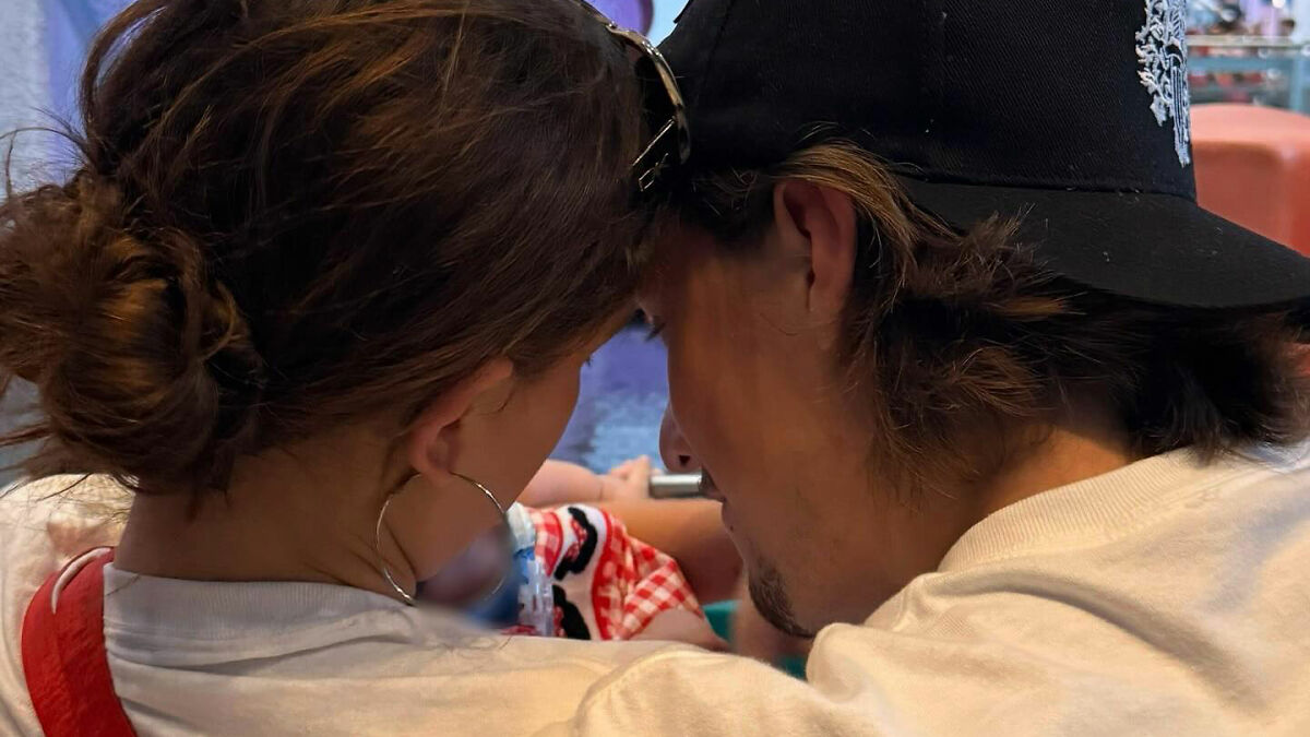 Couple closely looking at a newborn baby, highlighting viral theory about Millie Bobby Brown's newborn daughter.