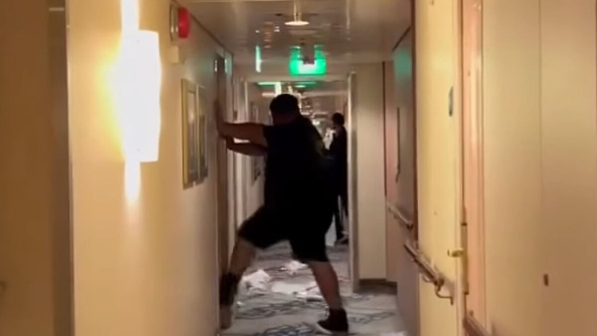 Man stumbling in narrow cruise ship hallway after being served multiple drinks, illustrating cruise passenger incident.
