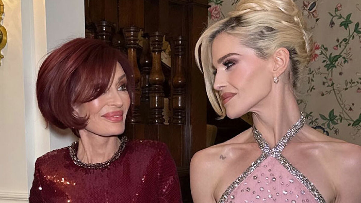 Sharon Osbourne and Kelly Osbourne wearing elegant dresses, sharing a moment at an indoor event.