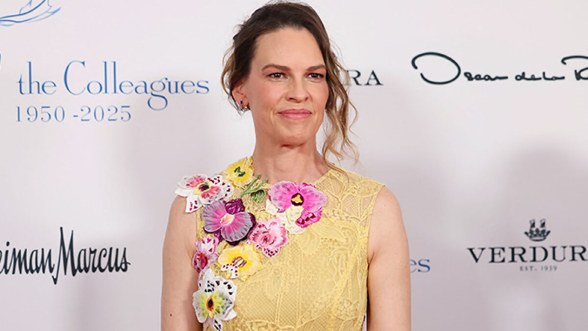 Hilary Swank at a charity event, wearing a yellow floral dress amid controversy involving mom of terminally ill kids.