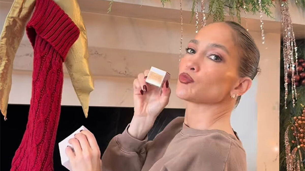 Jennifer Lopez posing near Christmas stockings holding a small box with fans noticing a depressing detail in video.
