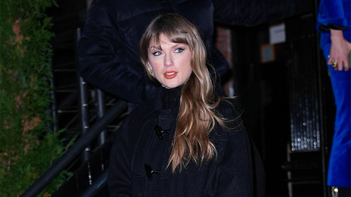 Taylor Swift wearing a black coat outdoors at night, amid rumors of coded white-nationalist messages.