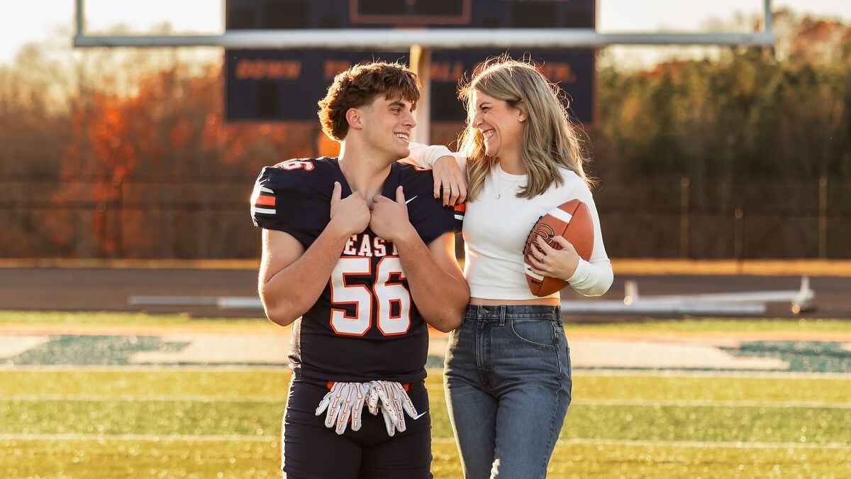 Mother and son smiling during a photoshoot on a football field, sparking a heated parenting debate.