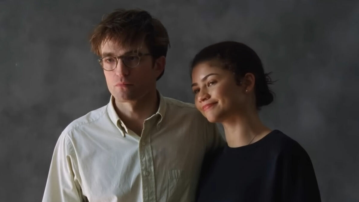Robert Pattinson and Zendaya posing together in a viral engagement ad with a soft gray background.