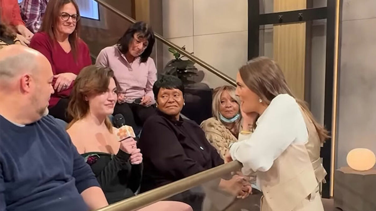 Fan wearing recreated Drew Barrymore 1989 Oscars dress speaking on a show while audience reacts with smiles.