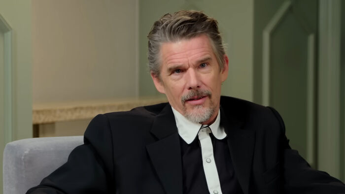 Actor Ethan Hawke in a black and white suit, sharing a story about chance encounters with celebrities.