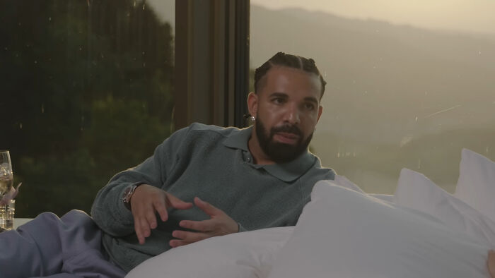 Man with braided hair and beard reclining indoors during sunset, illustrating moments of mere mortals running into celebrities.