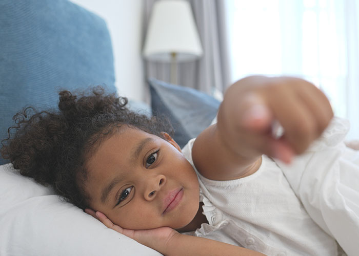 Child lying in bed pointing toward the camera, capturing an eerie moment related to creepy things kids said.