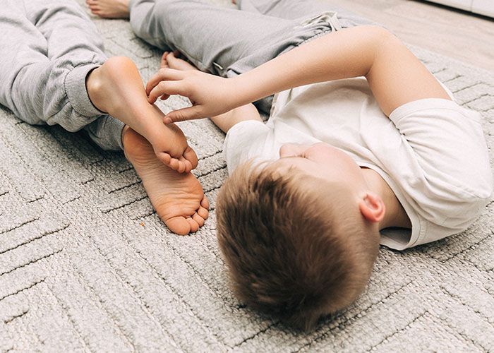 Two young kids lying on a carpeted floor, evoking creepy kids sayings that scare their parents intensely.