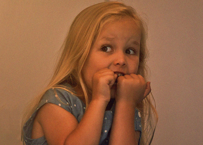 Young girl looking scared and anxious, illustrating creepy things kids said that frightened their parents.