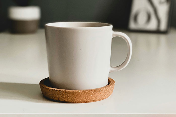 White ceramic mug on a cork coaster representing one of the worst gifts people have ever received in gift stories.