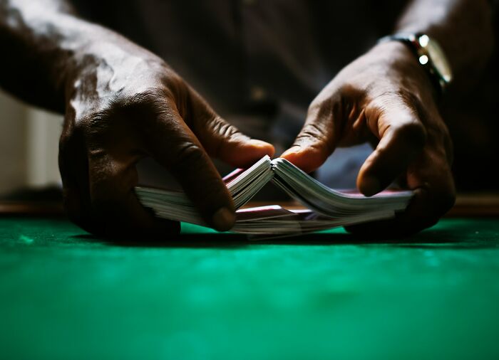 Hands expertly shuffling a deck of cards on a green table, illustrating facts that sound made up but are true.