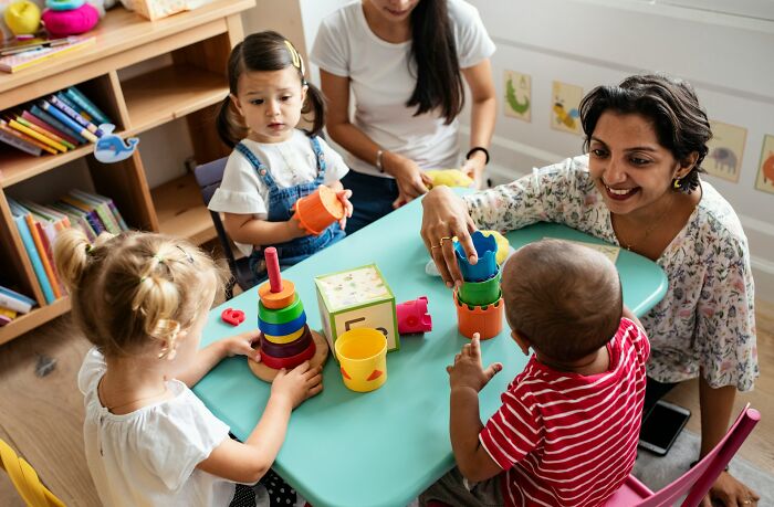 Caregiver interacting with children at a daycare, highlighting challenges faced by those who don’t get paid enough.