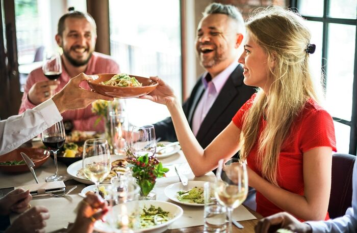 Group of friends enjoying a meal together while discussing harmless but toxic habits in a lively restaurant setting.