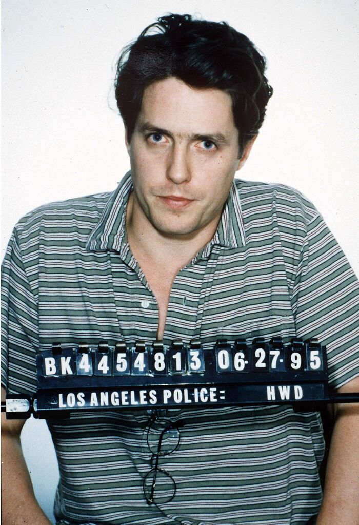Celebrity mugshot of a man in a striped shirt holding a Los Angeles Police identification board from 1995 arrest.