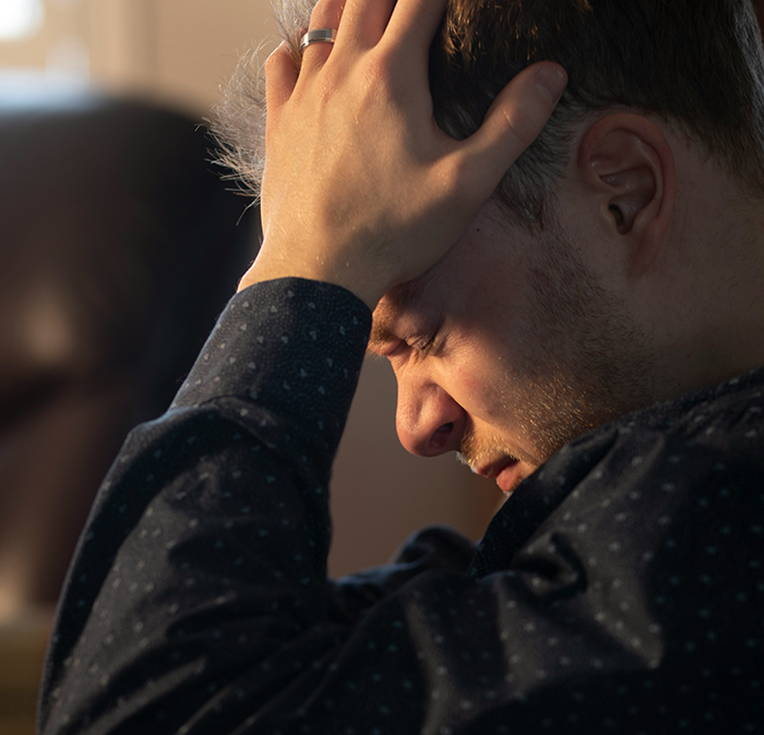 Upset man holding head, frustrated over dad not passing on craft skills while half-brothers start craft business.