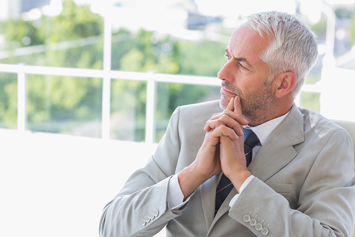 Mature man in a suit looking upset and thoughtful, reflecting on missed craft skills passed to half-brothers starting business.