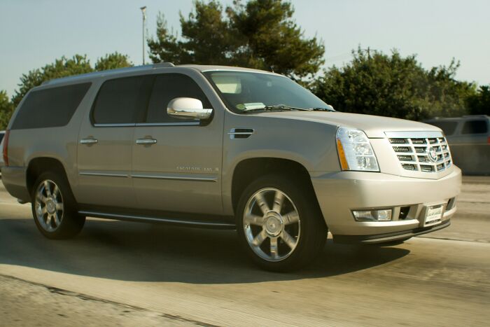 Silver luxury SUV driving on a highway surrounded by trees, illustrating an example of instant karma in action.