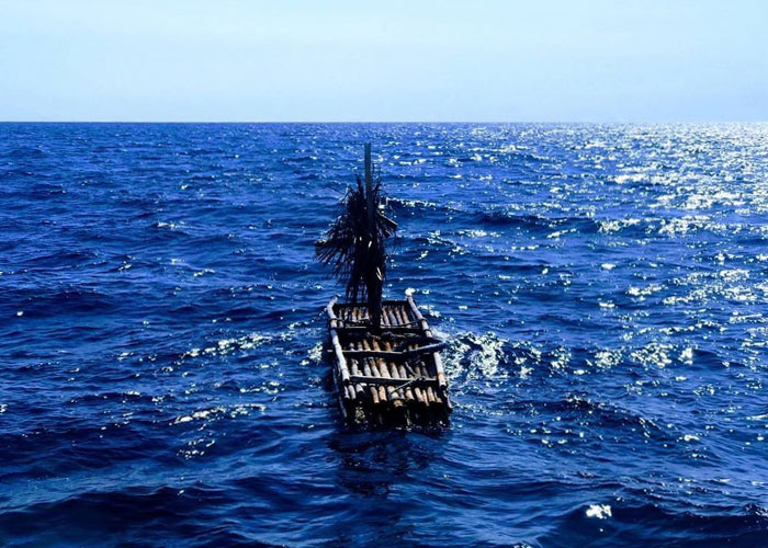 A small handmade wooden raft floating alone in the vast ocean, illustrating survival hacks that can be dangerous.