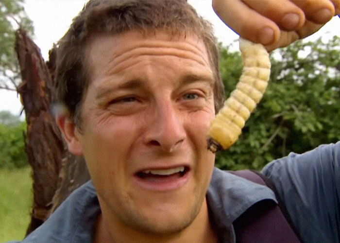 Man holding a large insect in wilderness showing survival hacks that can be useless and dangerous in outdoor situations