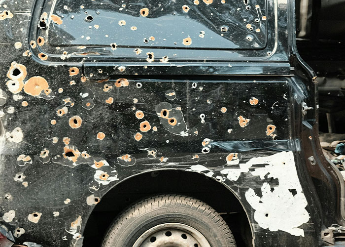 Close-up of a vehicle covered in bullet holes illustrating survival hacks that can be dangerous and ineffective.