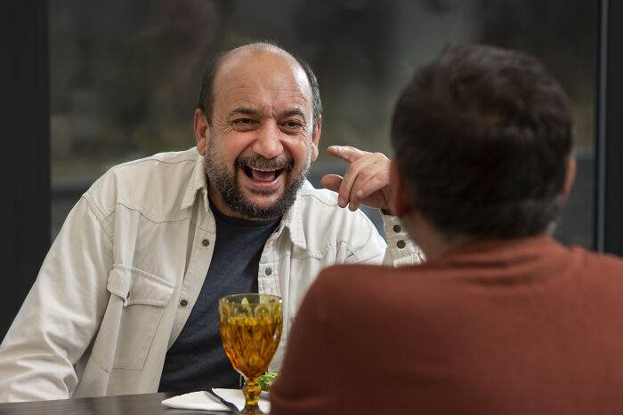 Two men enjoying a lively conversation over drinks, illustrating people who dated outside of their culture experiences.