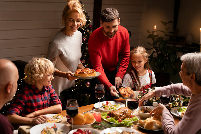 Family enjoying a holiday dinner together, sharing food and laughter in a warm multicultural gathering.