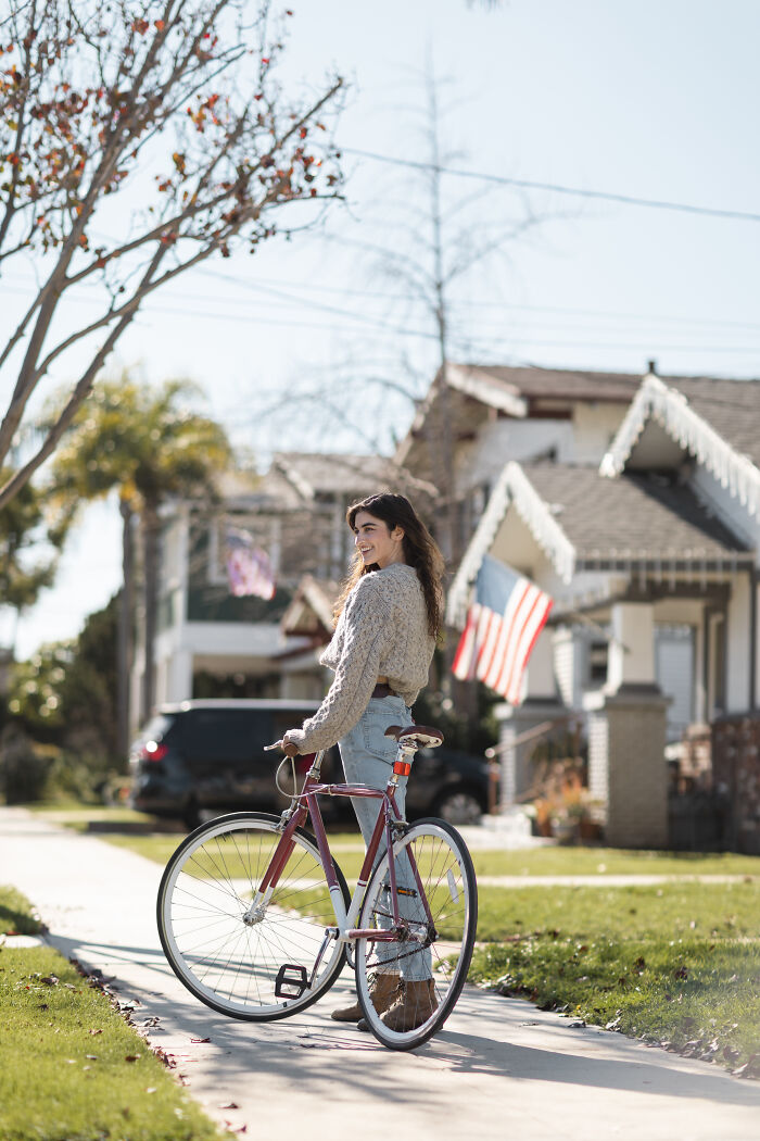 Young woman with bike on neighborhood sidewalk, representing people who dated outside of their culture sharing experiences.