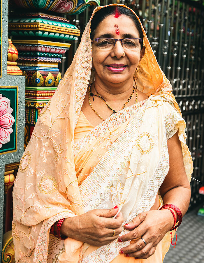 Smiling woman in traditional Indian attire standing by a colorful decorated gate, representing dating outside culture.