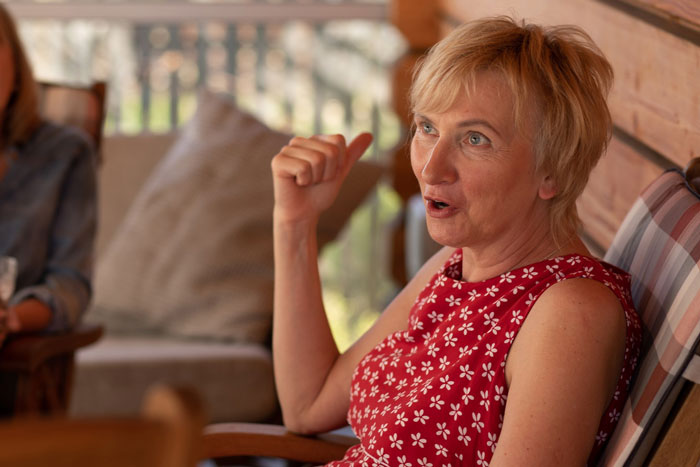 Woman in red floral dress expressing frustration while sitting indoors, depicting care for autistic brother and family demands. Woman in red floral dress expressing frustration while sitting indoors, depicting care for autistic brother and family demands.