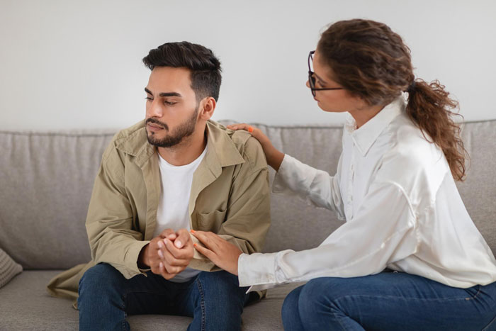 Woman comforting her autistic brother on a couch, showing care and support during a difficult moment at home. Woman comforting her autistic brother on a couch, showing care and support during a difficult moment at home.