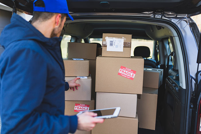 Delivery driver checking fragile packages in the back of a van related to woman’s shattered Christmas gift claim. Delivery driver checking fragile packages in the back of a van related to woman’s shattered Christmas gift claim.