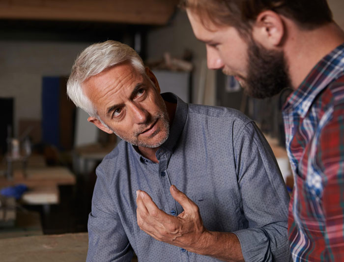 Middle-aged man explaining something seriously to a younger man, reflecting teen mad over car gift favoritism at Xmas. Middle-aged man explaining something seriously to a younger man, reflecting teen mad over car gift favoritism at Xmas.